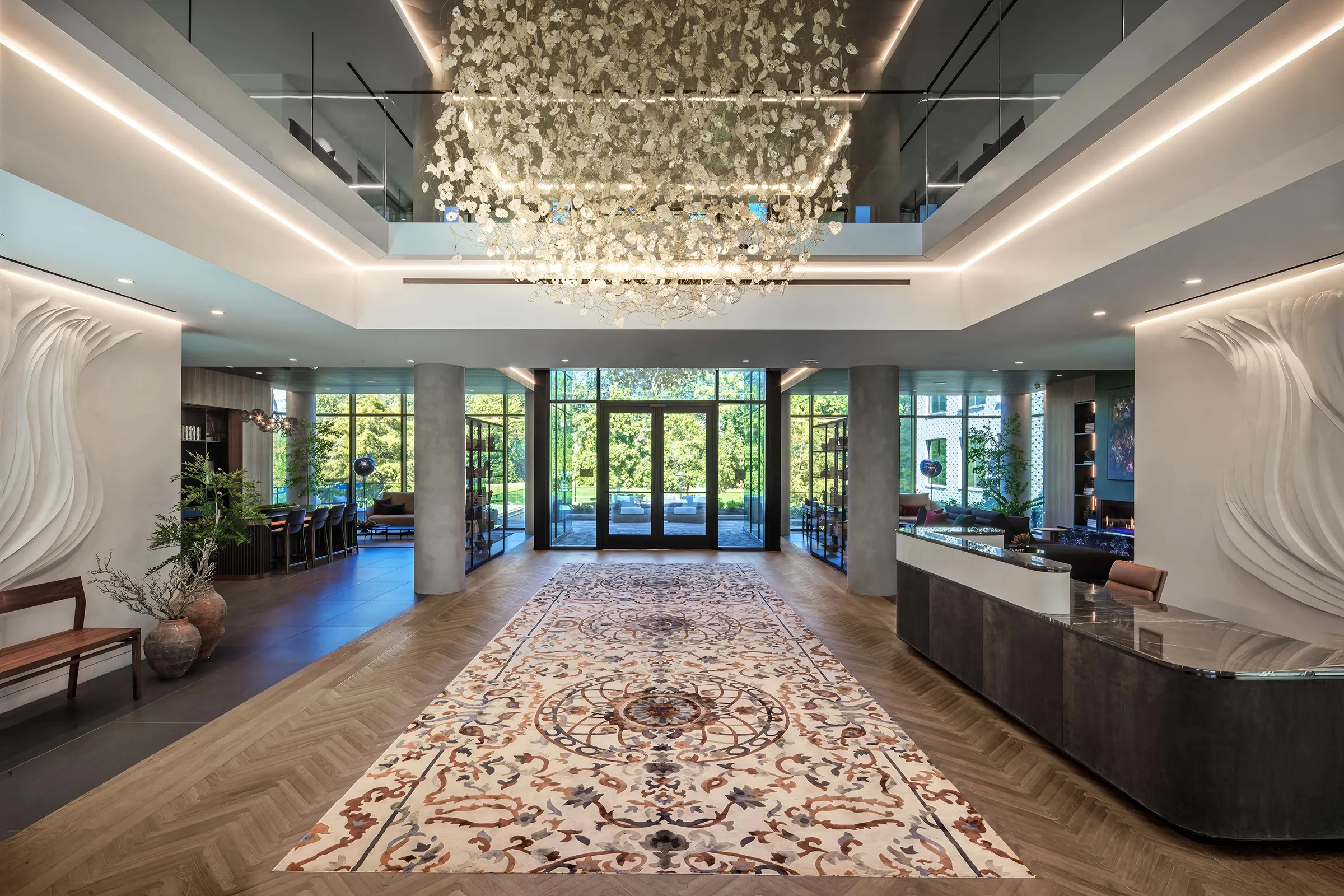 Spacious luxury apartment lobby with sculptural chandelier and patterned area rug